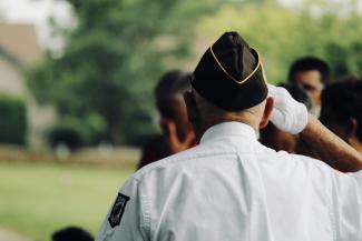 man wearing white uniform saluting by sydney Rae courtesy of Unsplash.