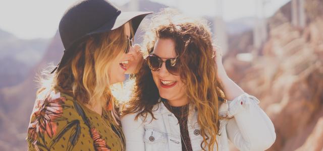 two women smiling while wearing sunglasses by Katie Treadway courtesy of Unsplash.